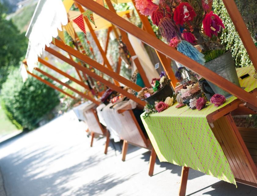 Outdoor stalls selling handmade crafts and decorations, set up in a leafy street.