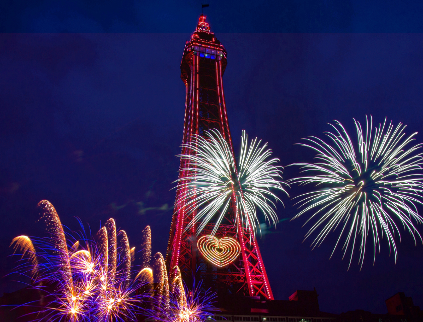 Fireworks exploding around the brightly lit Blackpool Tower at night.