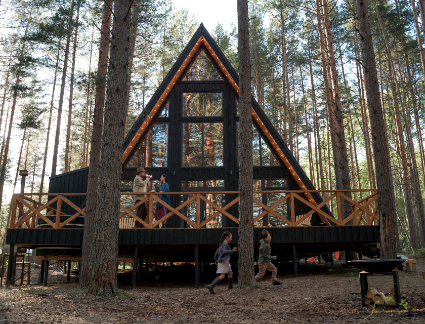 A-frame cabin glamping site in the UK forest with a wooden deck for family fun.