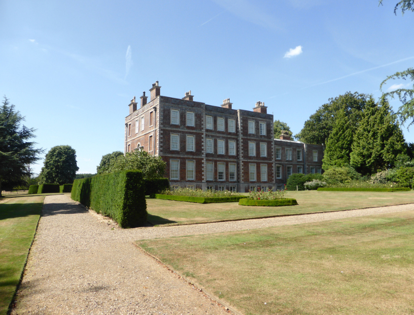 Gunby House stately mansion in Mablethorpe, Lincolnshire Surrounded by beautifully manicured gardens with gravel pathways, trimmed hedges, and expansive green lawns under a bright sky.